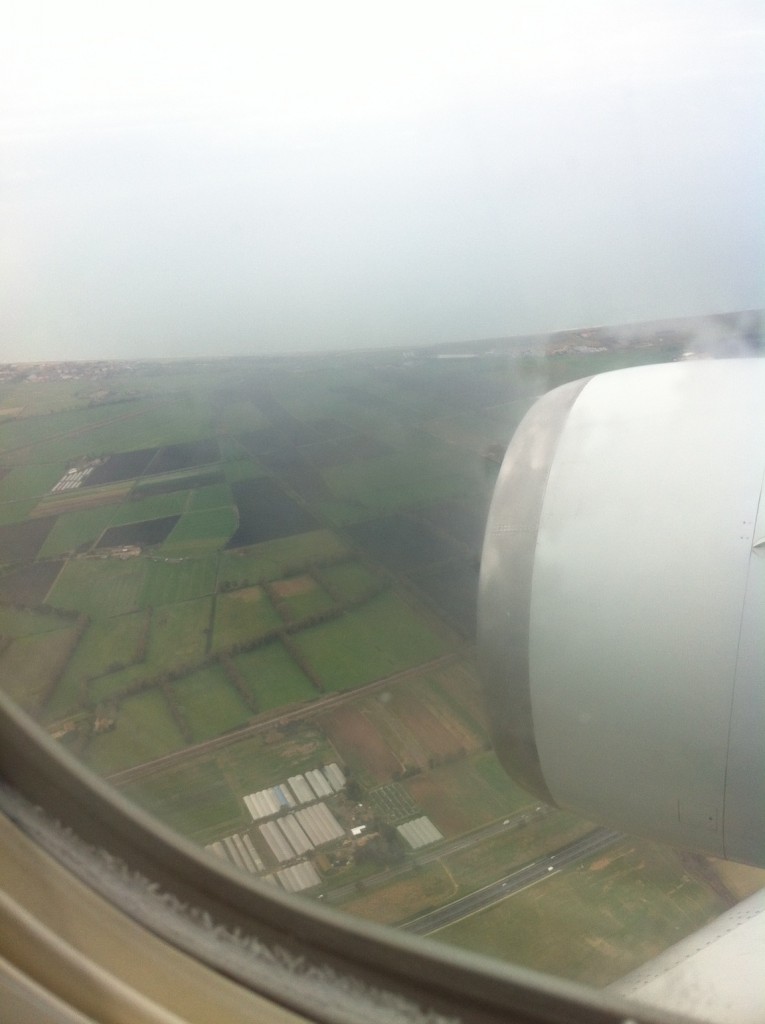 tuscany | Abroad101 Blog Aerial view of the landscape from an airplane window, showing green fields, roads, and an airplane engine.