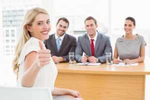 Woman gesturing thumbs up in front of corporate personnel office | Abroad101 Blog Woman gesturing thumbs up in front of corporate personnel office