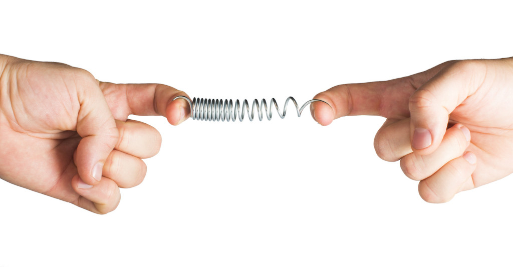 Stretched spring. Resistance and opposition metaphor | Abroad101 Blog Two hands stretching spring.Stretched spring. Resistance and opposition metaphor.