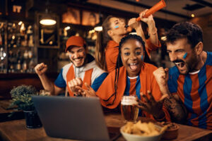 3 | Abroad101 Blog Students in a bar cheering and enjoying a game, representing the importance of budget-friendly social activities while studying abroad.