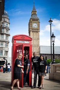 Students attending University of Westminster's summer school program standing by a red telephone booth in London with Big Ben in the background.