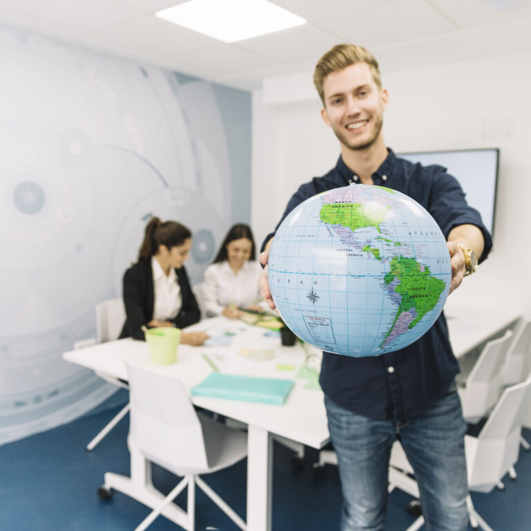 happy-young-businessman-holding-globe-office | Abroad101 Blog