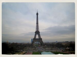View of the Eiffel Tower in Paris on a cloudy day, seen from the Trocadéro Gardens with the Champ de Mars stretching out beneath the tower.