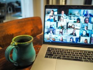chris-montgomery-smgTvepind4-unsplash | Abroad101 Blog Laptop displaying a virtual classroom with multiple students on video call, next to a coffee mug—representing the convenience of online summer learning.