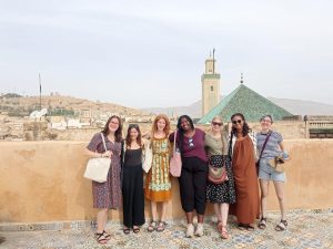 rabat group | Abroad101 Blog APA study-abroad students on a tiled rooftop in Rabat, Morocco, with a green-tiled medina minaret.