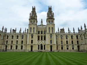 1234 | Abroad101 Blog Grand Gothic-style college building with twin towers and manicured lawn at the University of Oxford, a top choice for law study abroad.