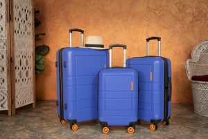 american-green-travel-ji5XMfO3dXY-unsplash (1) | Abroad101 Blog Set of three blue hard-shell suitcases with spinner wheels and a hat, illustrating the tip to avoid overpacking and choosing manageable luggage.