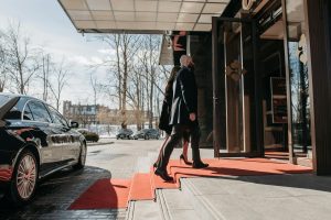 pexels-pavel-danilyuk-7594124 | Abroad101 Blog Two travelers walk up a red carpet into a building—arrival and check-in at temporary accommodation during a move abroad.