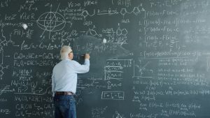 vitaly-gariev-81-Sn_ab6IQ-unsplash | Abroad101 Blog Teacher writes on a chalkboard covered with equations and diagrams, illustrating classroom instruction and the value of ongoing professional development.
