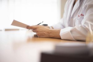 pexels-paloma-gil-1205746-16204144 | Abroad101 Blog Doctor in a white coat reviewing medical paperwork at a desk, representing healthcare planning and insurance guidance for students studying abroad.