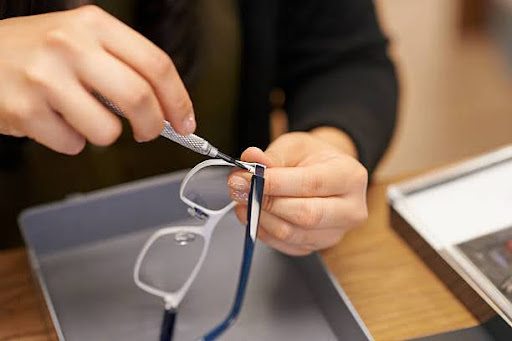 Close-up of someone repairing broken eyeglasses with a small screwdriver.