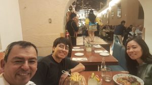 Studying Abroad with IPSL at Cusco, Peru | Abroad101 Blog Group seated at a restaurant in Cusco with a shared meal and a cultural performance in the background.