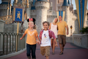 Florida provides affordable fun beyond the theme parks | Abroad101 Blog Two children wearing Disney-themed clothing run hand in hand in front of Cinderella Castle at Walt Disney World, with their parents walking behind them.