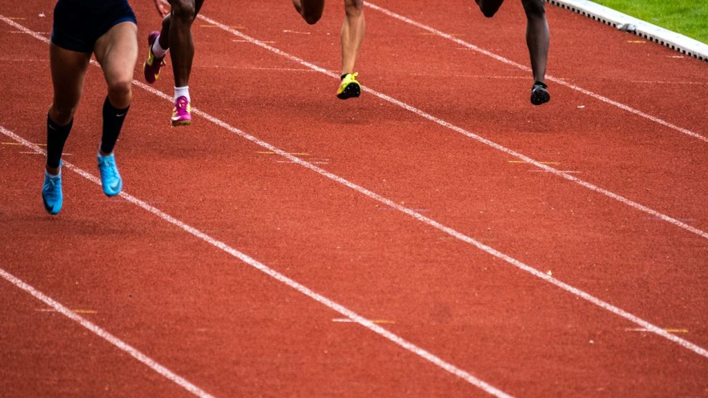 Runners moving around an outdoor athletics track during a training session.