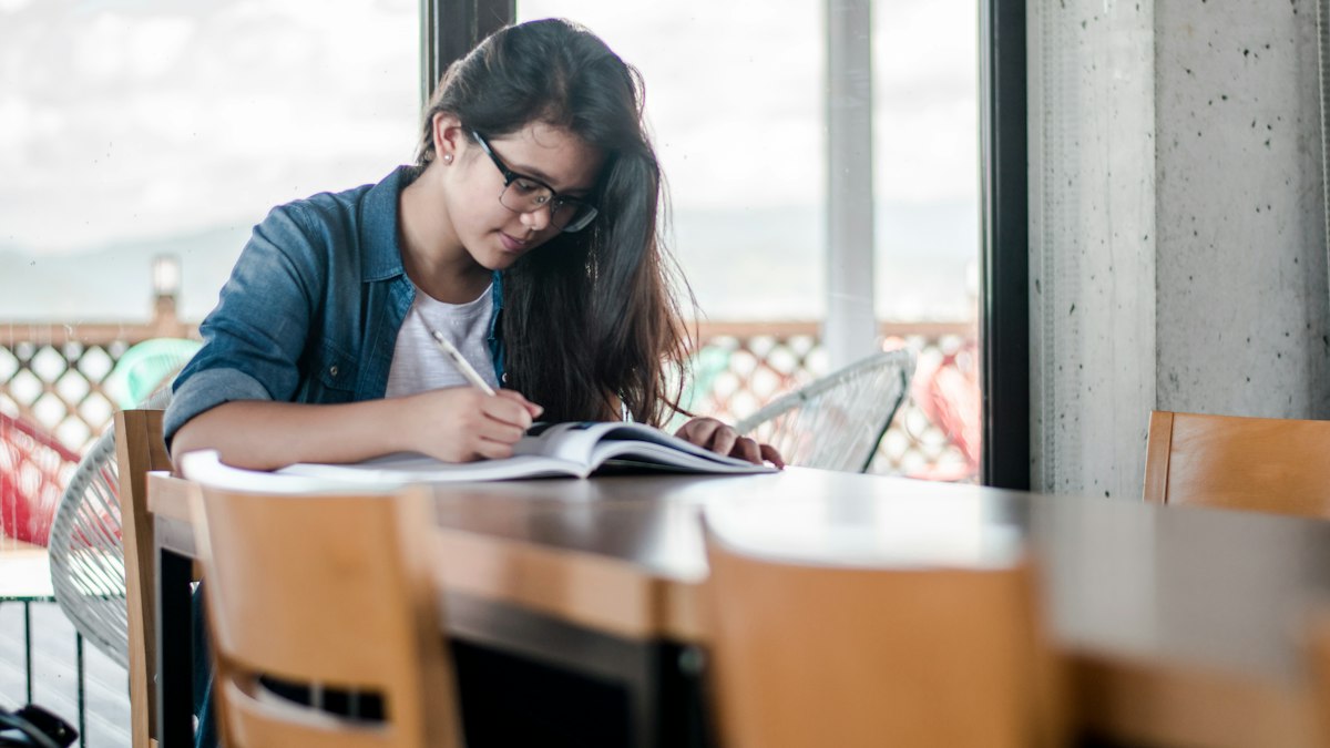 Study abroad deposit checklist — student reviewing notes | Abroad101 Blog Person writing in an open notebook while reviewing information at a desk