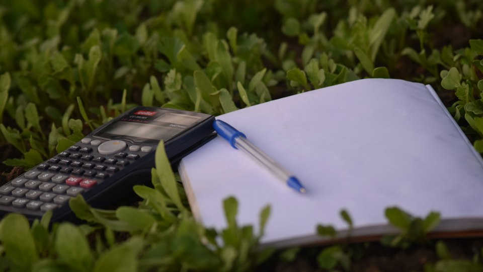 Pen and paperwork beside a calculator on a desk